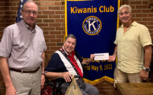 Del Ray Artisans Director of Fundraising Events Joe Franklin (L) and President Drew Cariaso (R) accept a donation from Kiwanis Alexandria President Stephen Blood in 2019