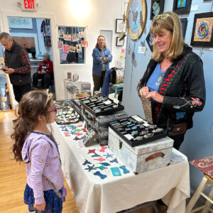 Nancy Kline Art helping a young customer at Del Ray Artisans' Holiday Market 2023 (Photo courtesy of Tamara Wilkerson) 